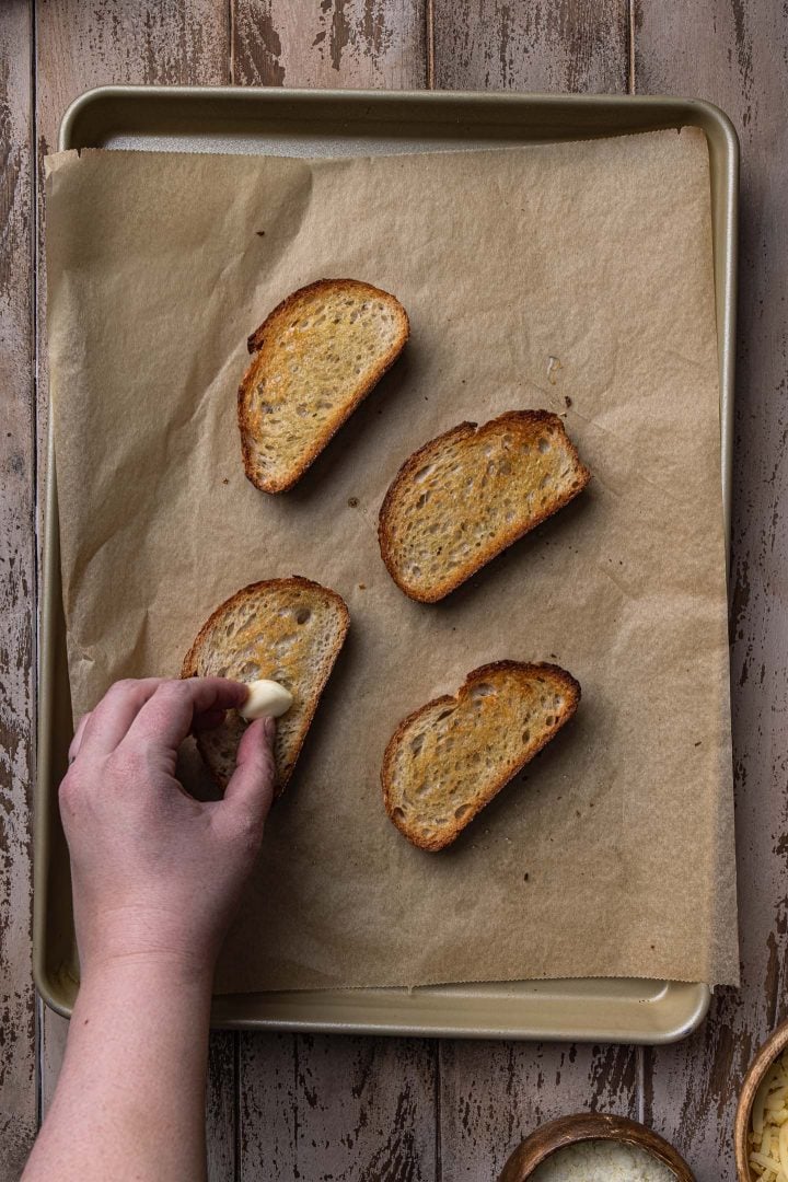 Rubbing the toasted bread with garlic.