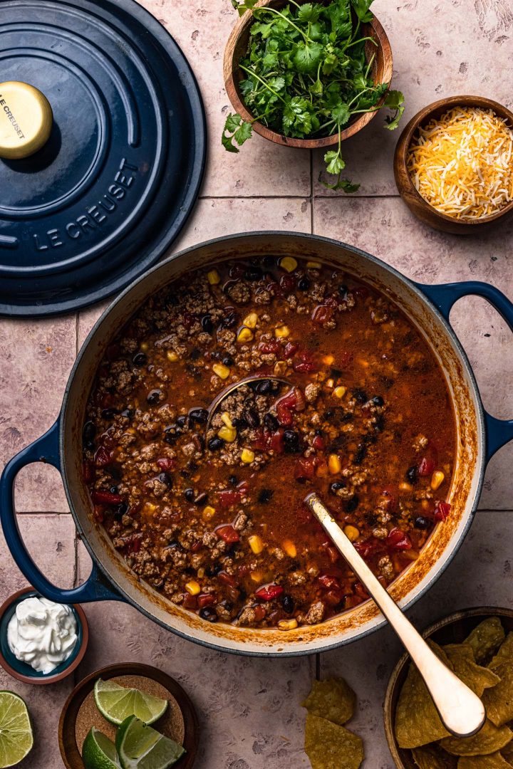 A pot of taco soup with toppings served on the side.