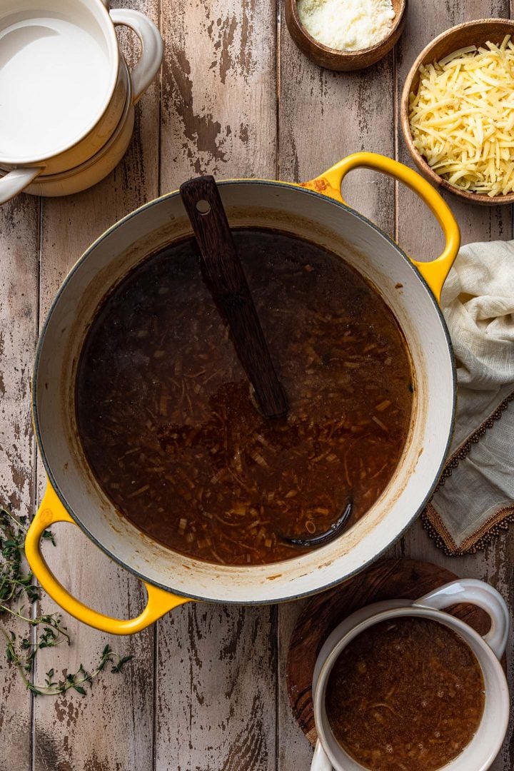 A pot of French onion soup and an individual bowl with the soup.