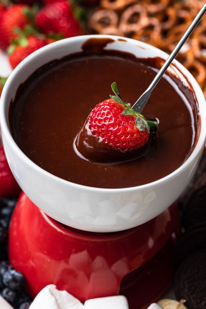 A strawberry being dipped into chocolate fondue.