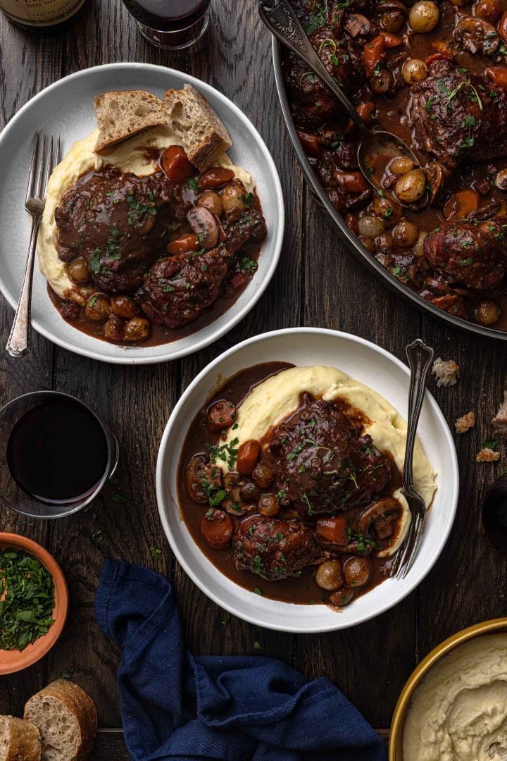An overhead photo of two bowls of coq au vin over mashed potatoes.