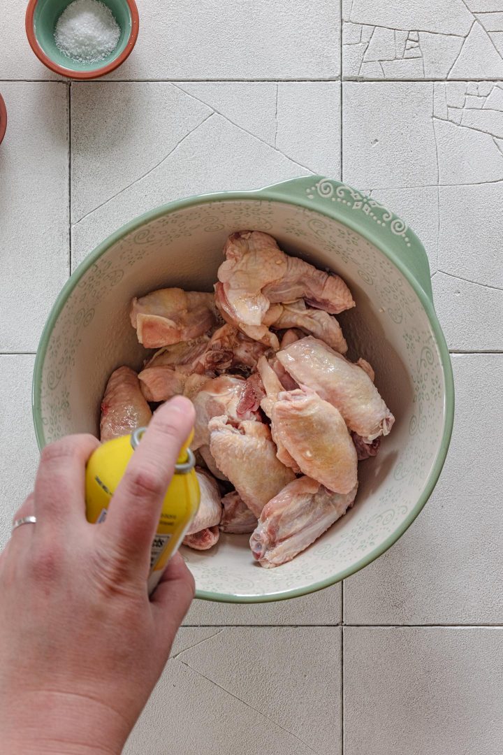 Spraying chicken with nonstick spray.