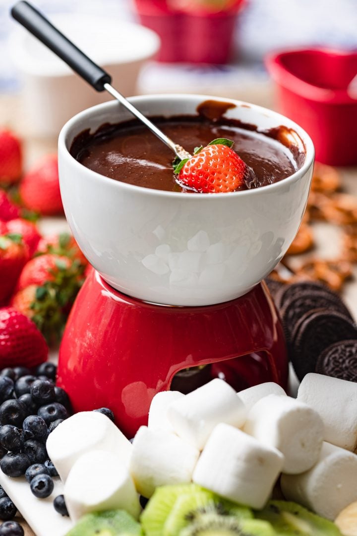 A pot of fondue, served with different treats and fruits to dunk on the chocolate.