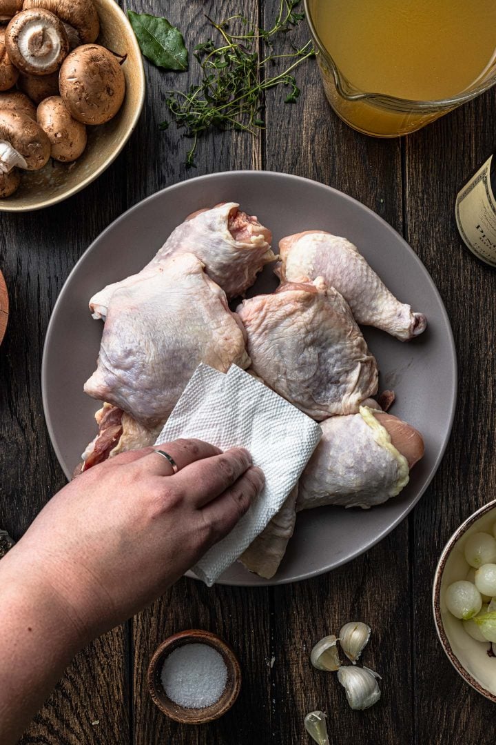 Patting the chicken dry with a paper towel.