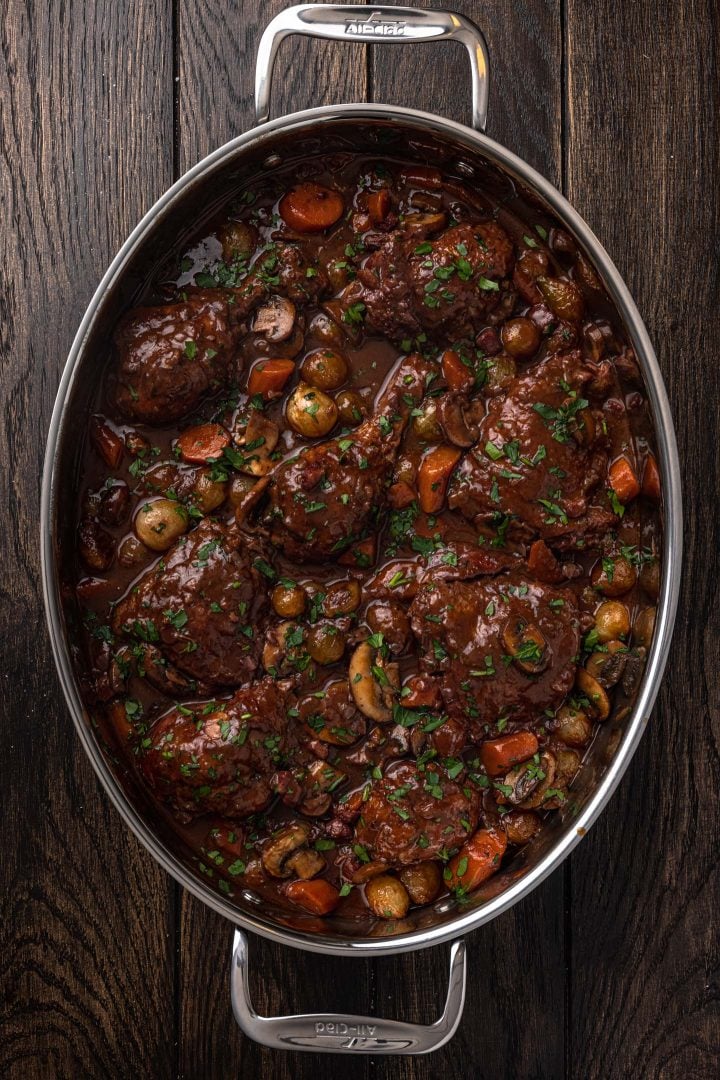 Coq au Vin in a serving dish, garnished with parsley.