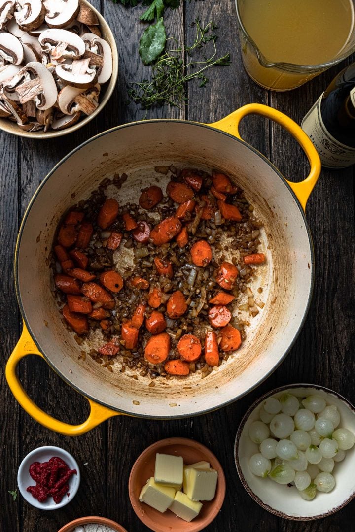 Sautéed onions and carrots in a pot.