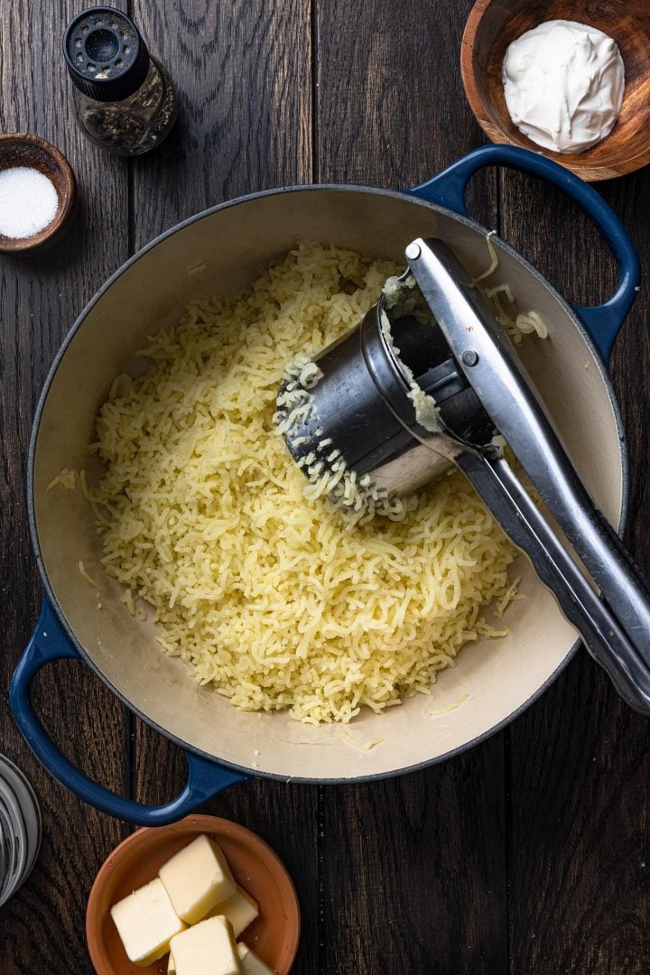 Ricing the potatoes back into the pot.