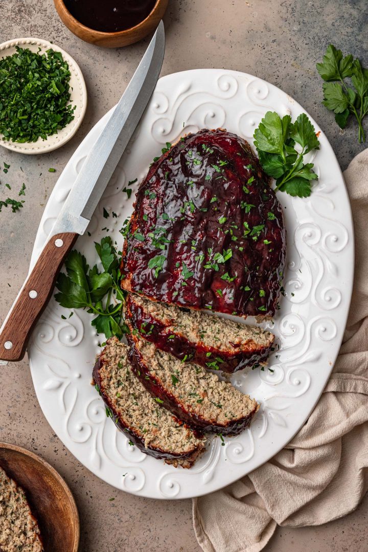 A turkey meatloaf on a platter, glazed with a balsamic glaze and garnished with parsley.