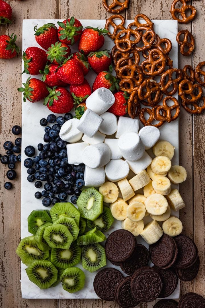 A photo of all the dippers: pretzels, strawberries, marshmallows, blueberries, bananas, kiwi, Oreos.