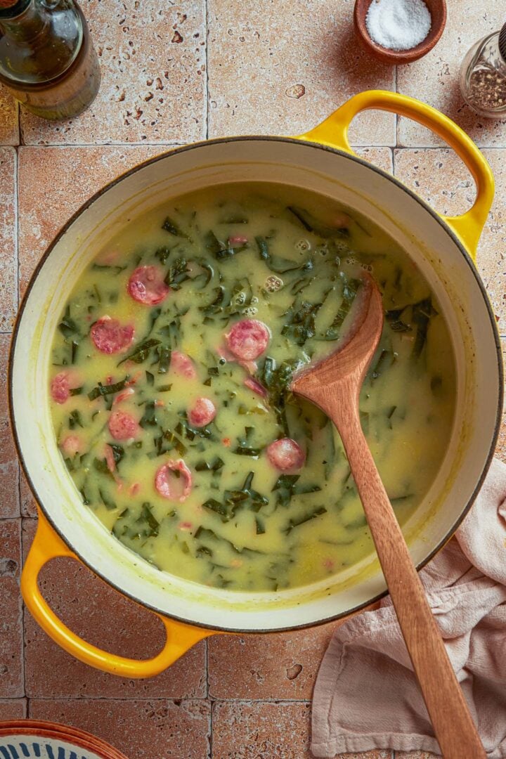A pot of caldo verde soup with a wooden spoon.
