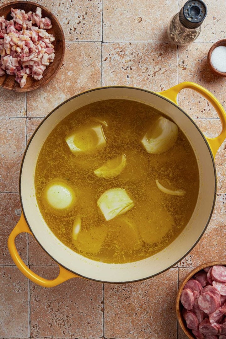 A pot with onion, garlic, potatoes, olive oil and broth.
