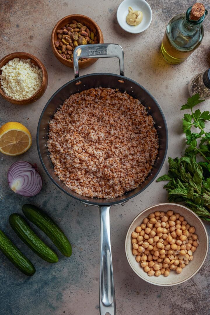 A photo of a pot with cooked bulgur wheat, along with all of the other ingredients to make this recipe. 