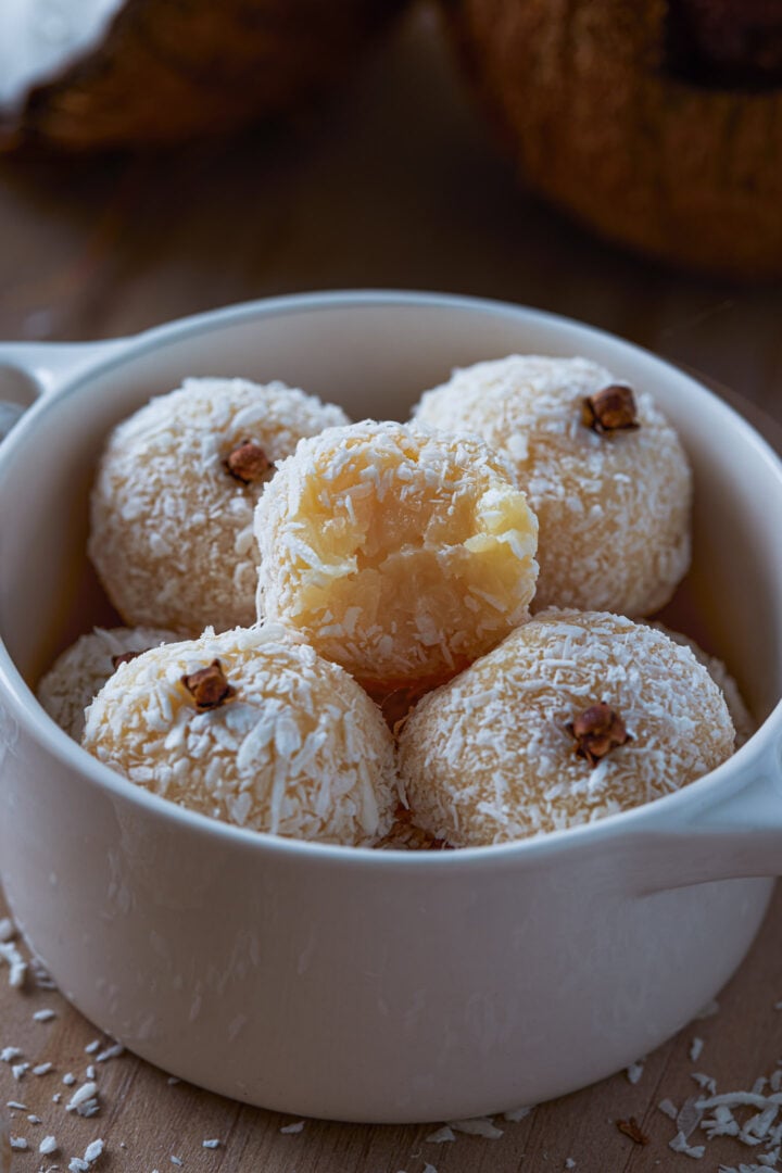 A pile of the coconut balls with one of them showing the creamy interior.