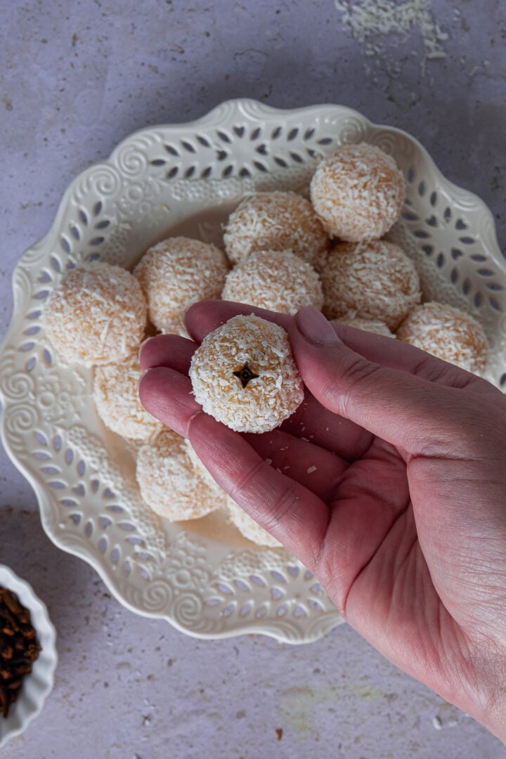 A hand holding one of the coconut truffles.