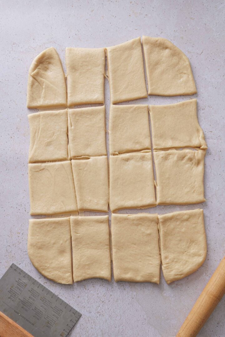 Overhead photo of the dough cut into 16 equal pieces for shaping Brazilian sweet condensed milk buns.