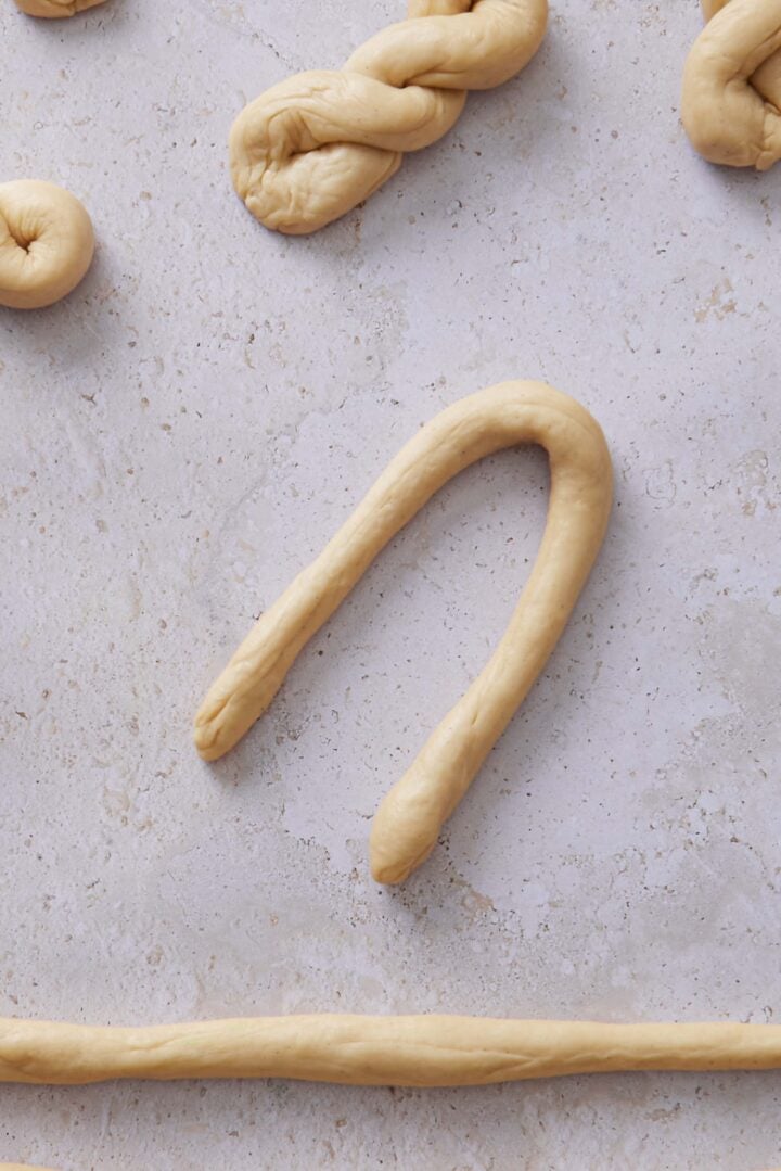 Close-up overhead photo of one dough rope folded in half into a U shape for shaping the buns.