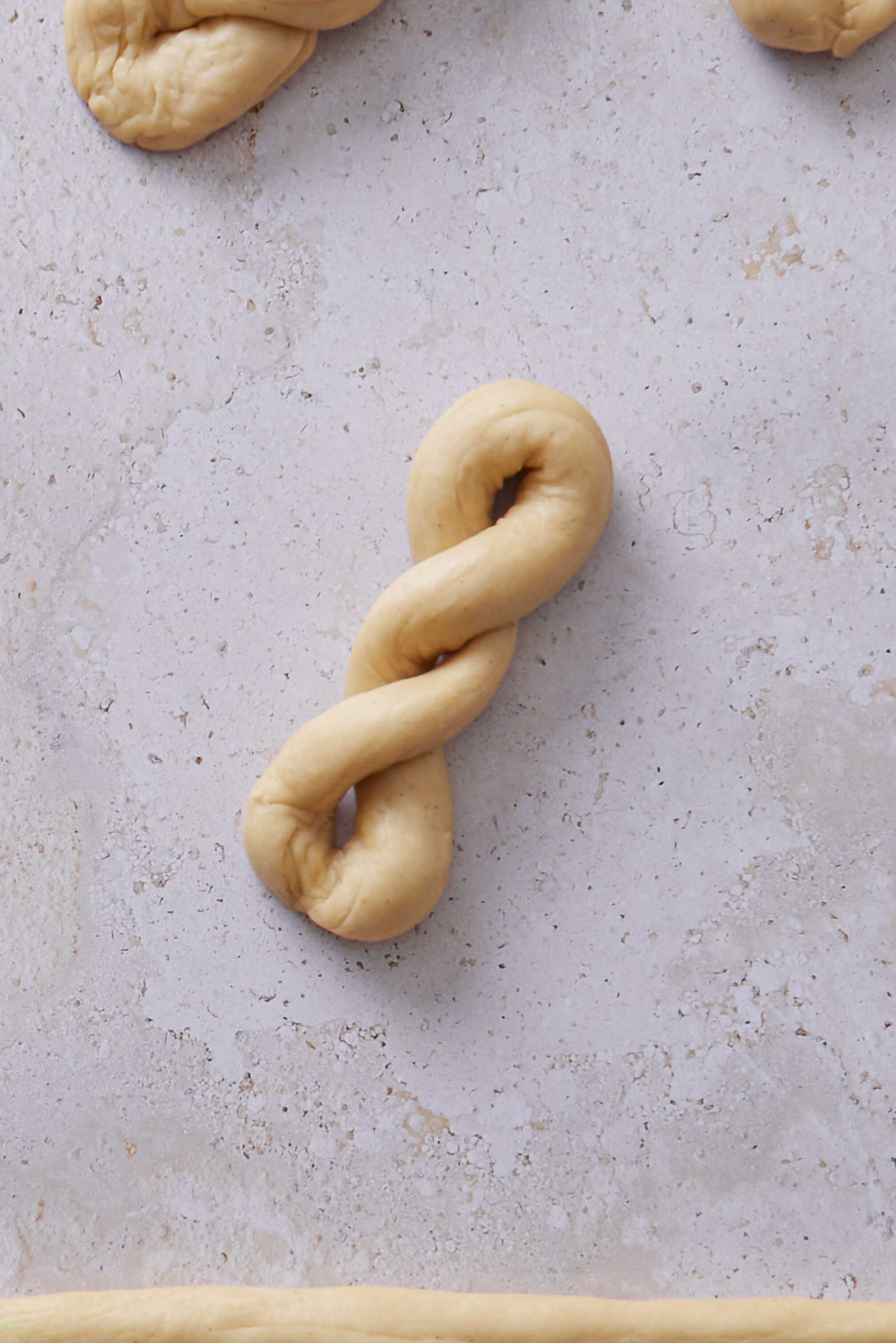 Overhead photo of one finished twisted bun shape with other shaped buns in the background.