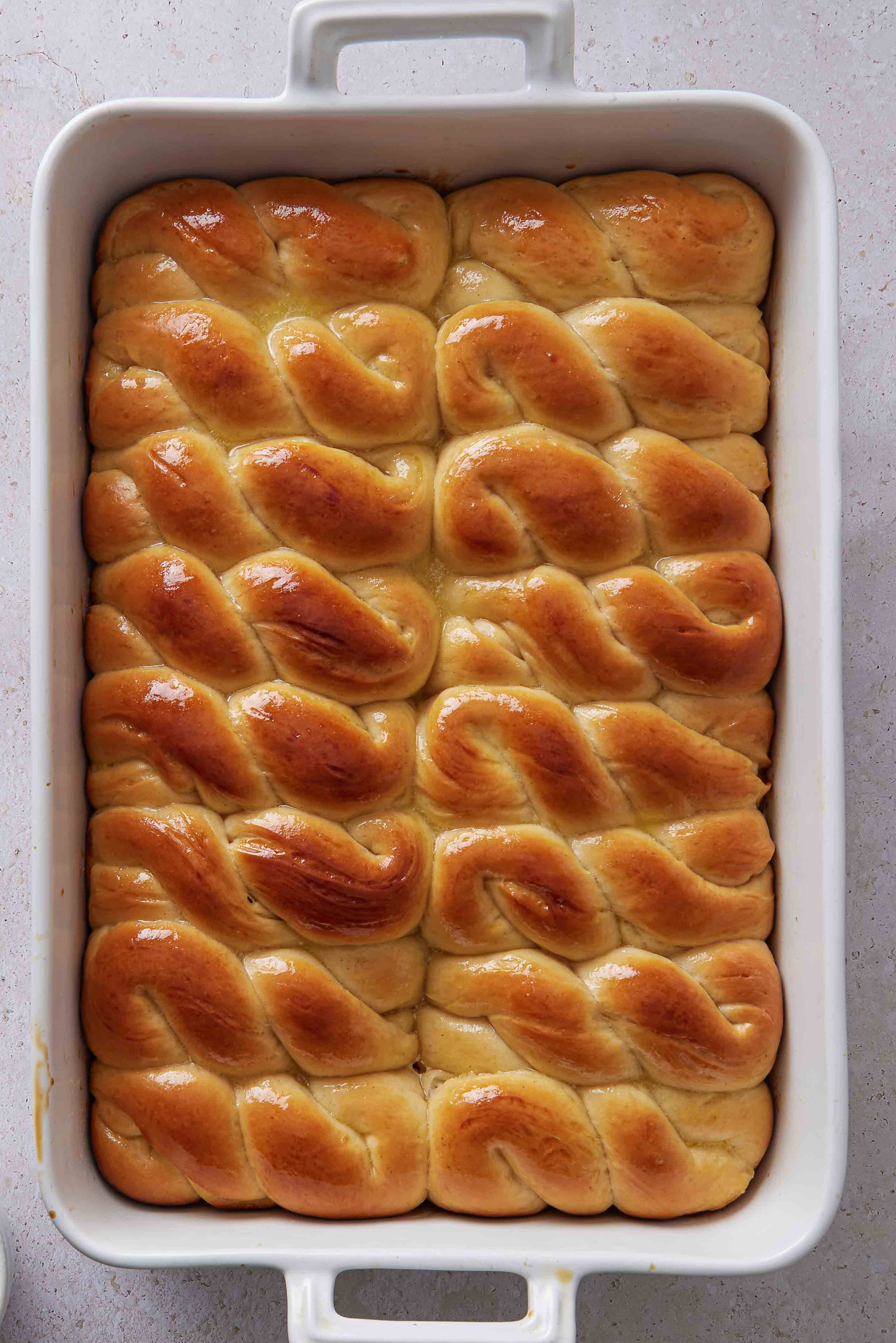Overhead photo of the baked buns in the white baking dish, golden brown and glossy from the melted butter.