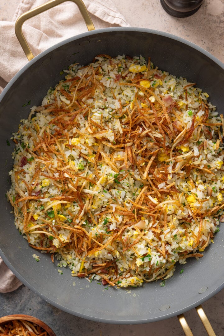 Brazilian arroz biro biro (Brazilian fried rice) with bacon, eggs, herbs, and crispy batata palha in a skillet
