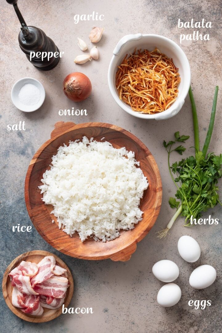 Ingredients for Brazilian fried rice with rice, bacon, eggs, onion, garlic, parsley, and batata palha