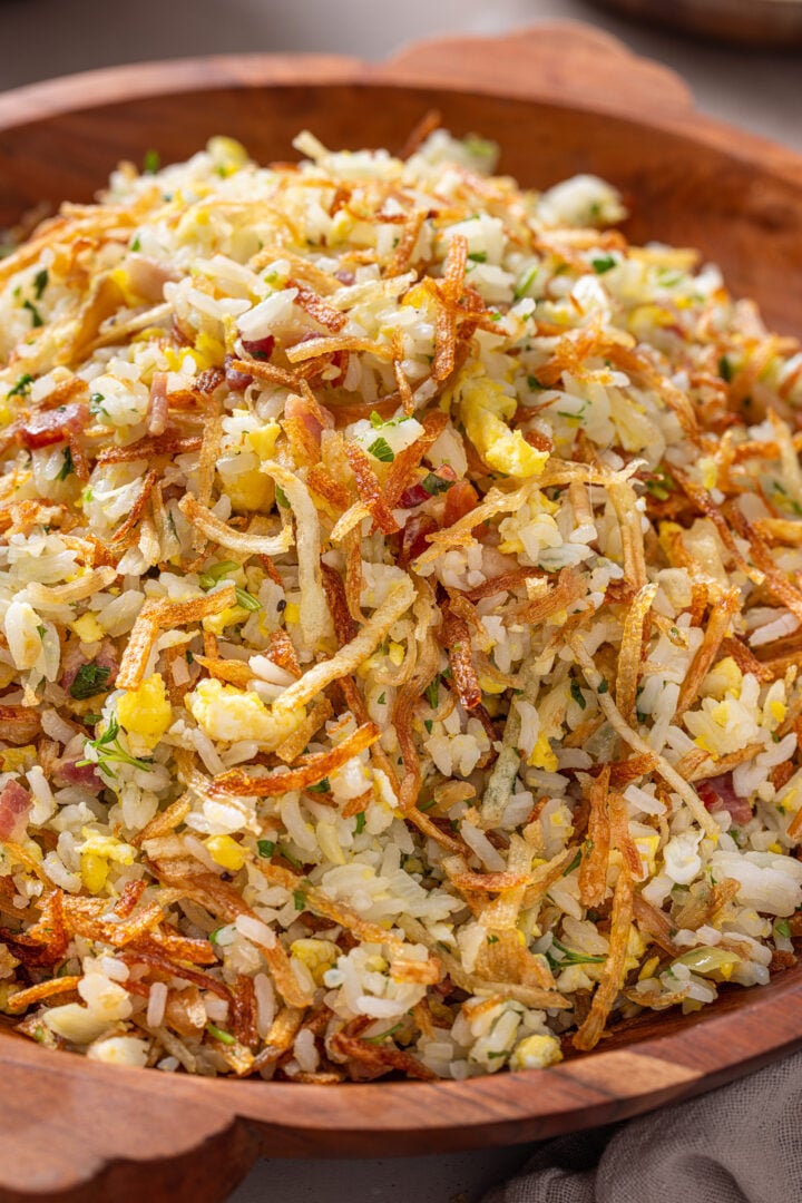 Close-up of arroz biro biro with fluffy rice, crispy bacon, scrambled eggs, and crunchy batata palha