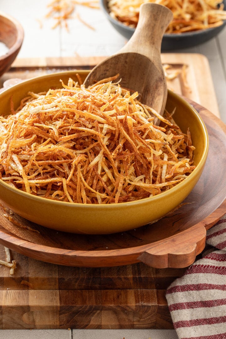 Bowl of homemade batata palha filled with crispy golden Brazilian shoestring potatoes.