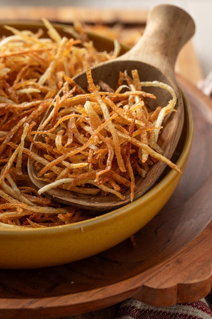 Close-up of crispy Brazilian batata palha showing thin, golden shoestring potatoes and crunchy texture.