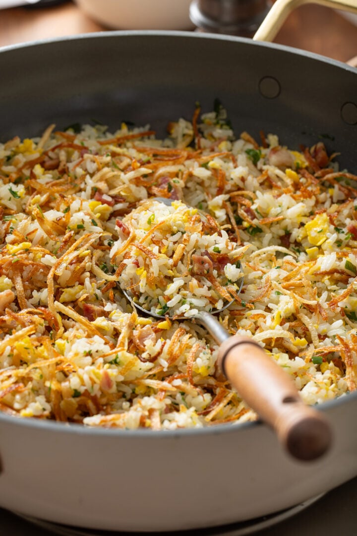 Spoon scooping arroz biro biro showing texture of rice, eggs, bacon, and batata palha