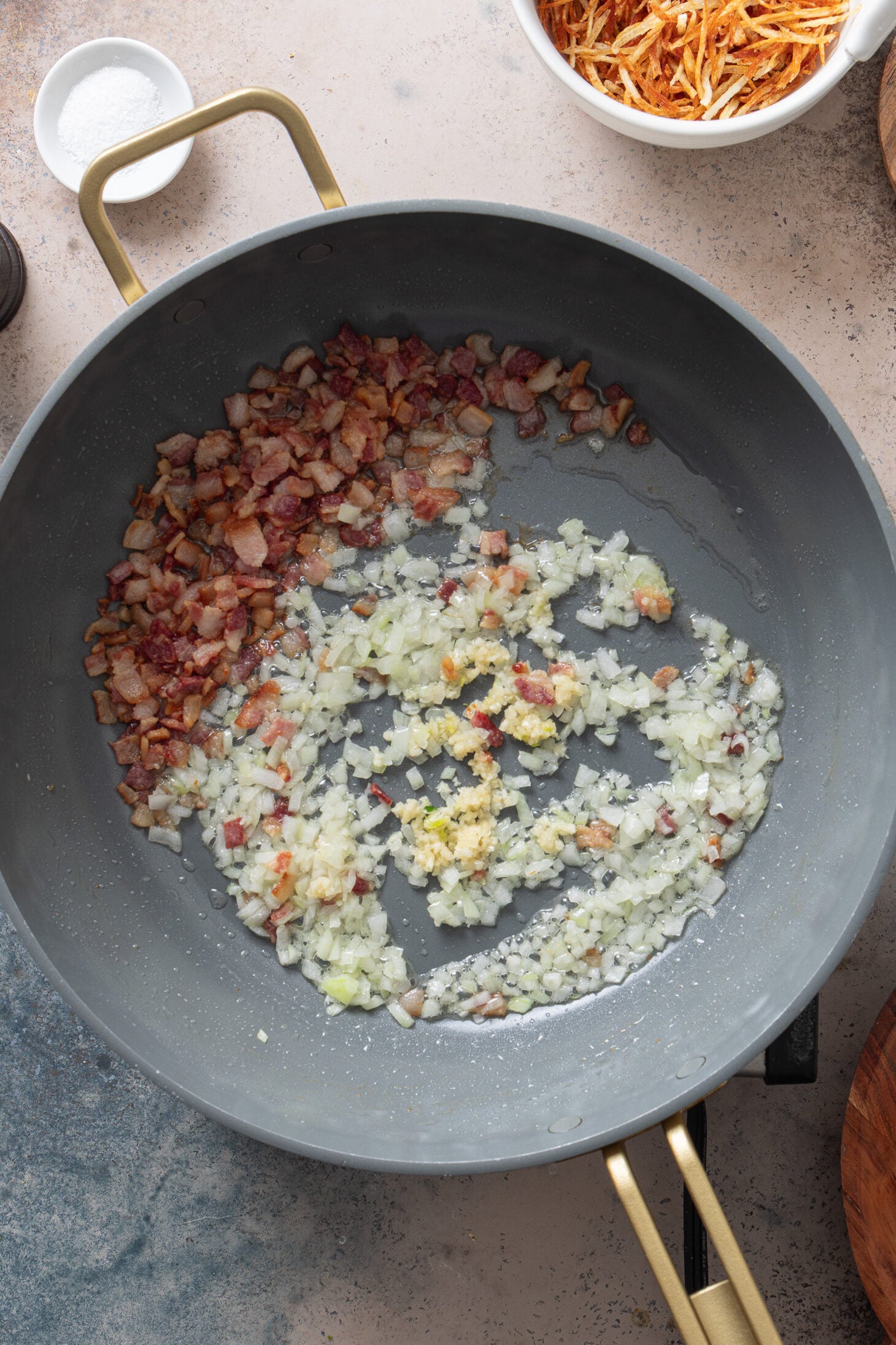 Onion and garlic sautéing with bacon in a skillet for arroz biro biro