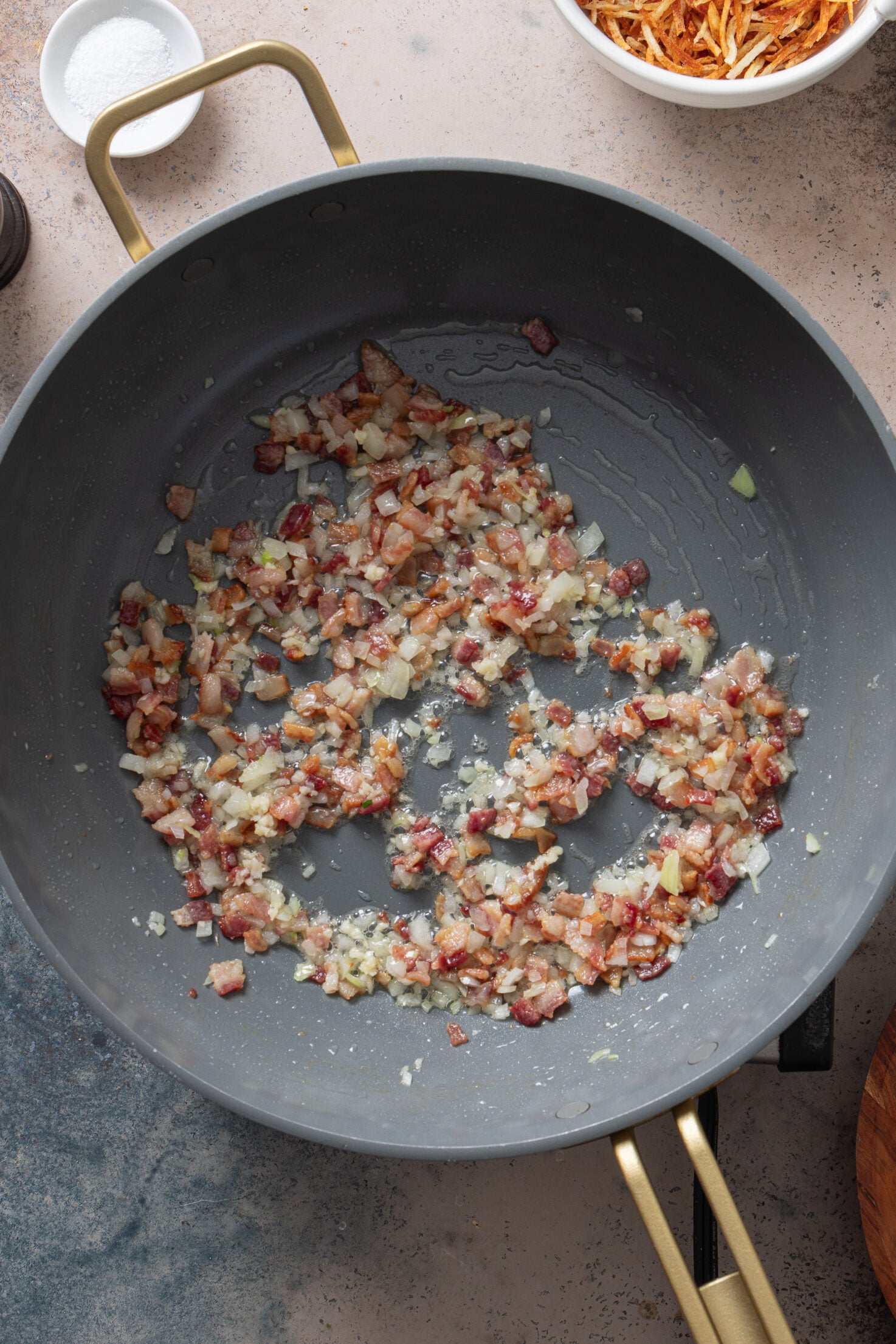 Bacon, onion, and garlic cooking in a skillet for Brazilian fried rice