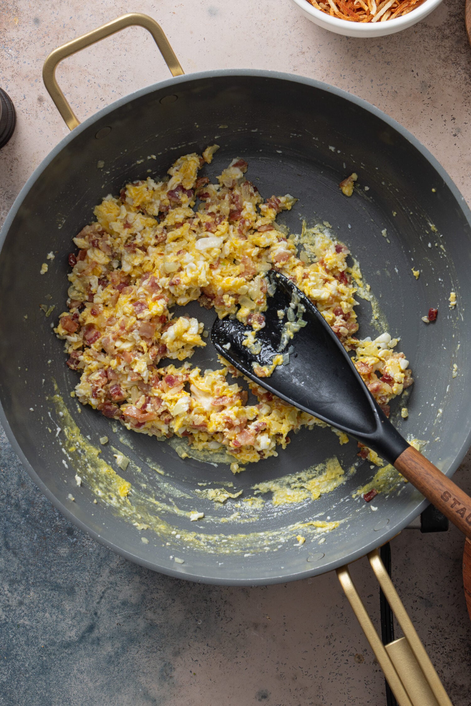Eggs scrambling with bacon and onions in skillet for arroz biro biro
