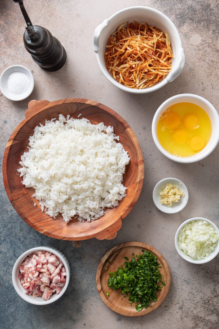 Ingredients for arroz biro biro including rice, bacon, eggs, onion, garlic, herbs, and batata palha
