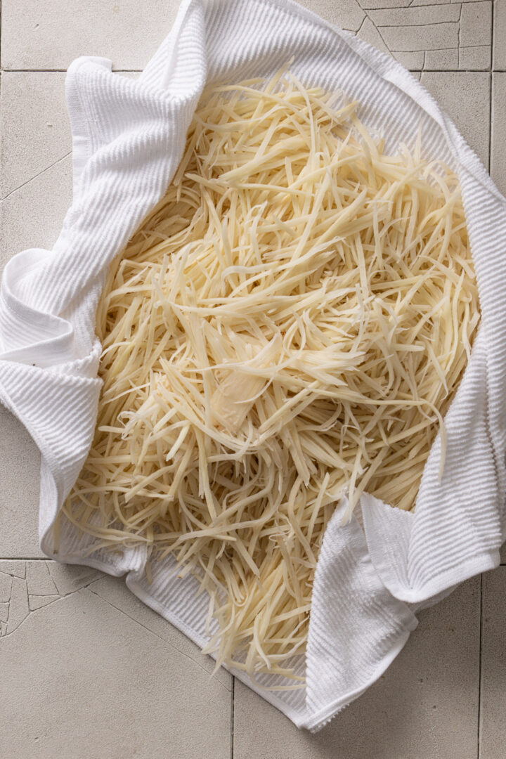 Julienned potatoes drying on a kitchen towel before frying.