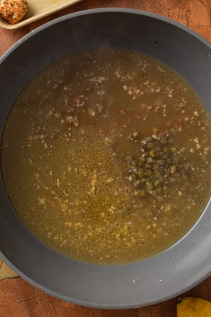 Chicken broth and capers added to skillet to deglaze and start the lemon piccata sauce
