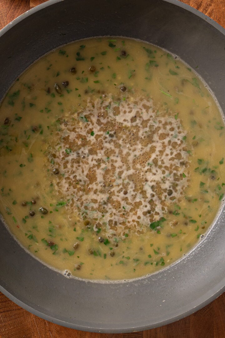 Lemon piccata sauce simmering in skillet with capers and parsley