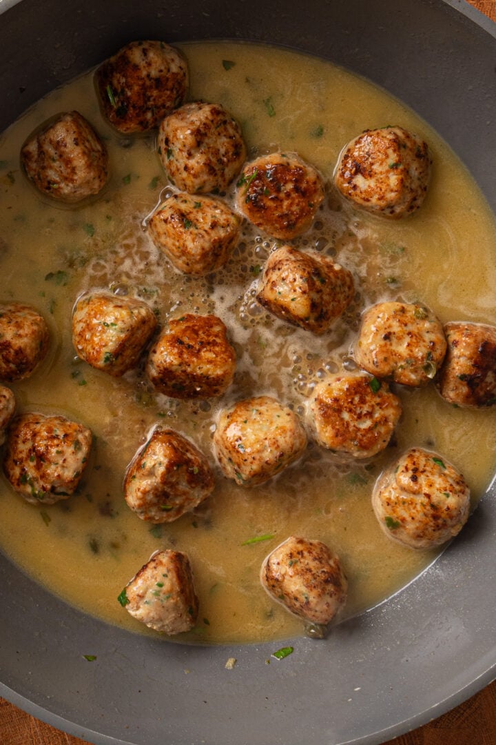 Chicken piccata meatballs simmering in lemon caper sauce until fully cooked and juicy