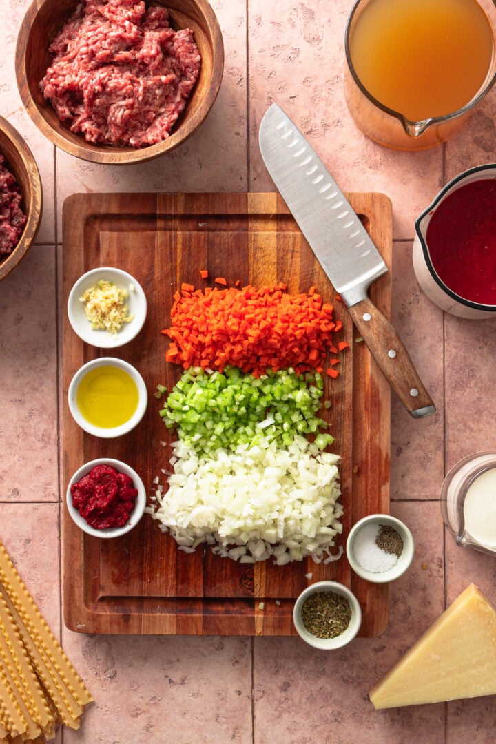 Prepped ingredients for creamy lasagna soup including diced onion, carrot, celery, garlic, and ground meat