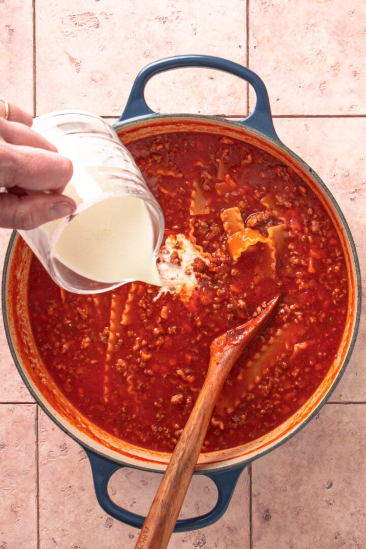 Heavy cream being stirred into lasagna soup