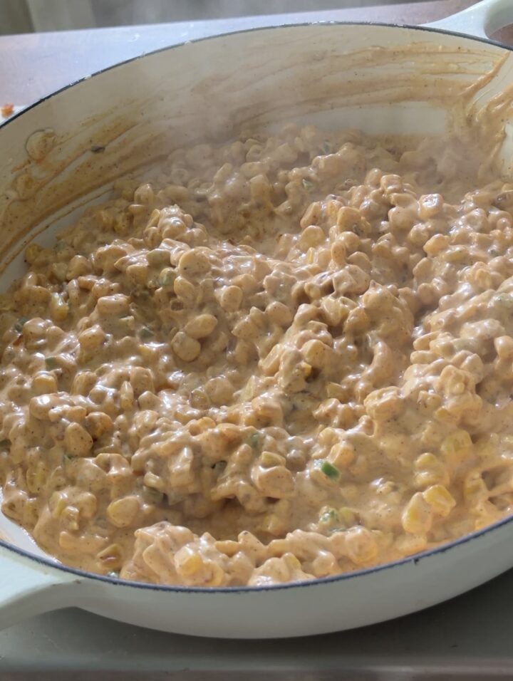 Creamy corn mixture for Mexican street corn dip stirred in a skillet before adding cheese