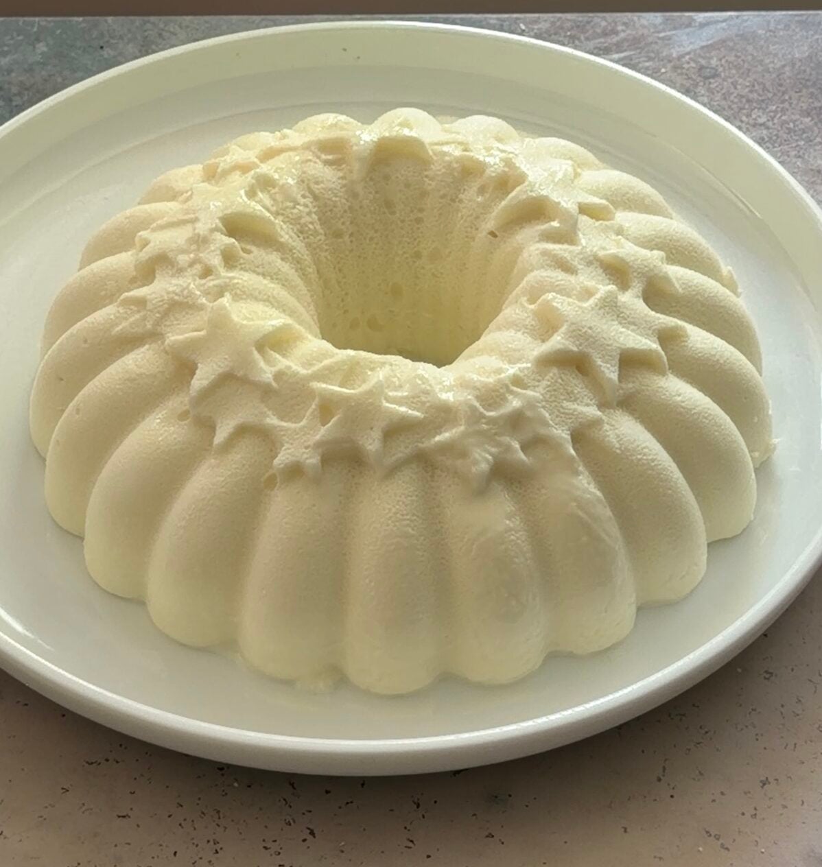 Freshly unmolded Brazilian coconut pudding (manjar branco) on a white platter before topping.
