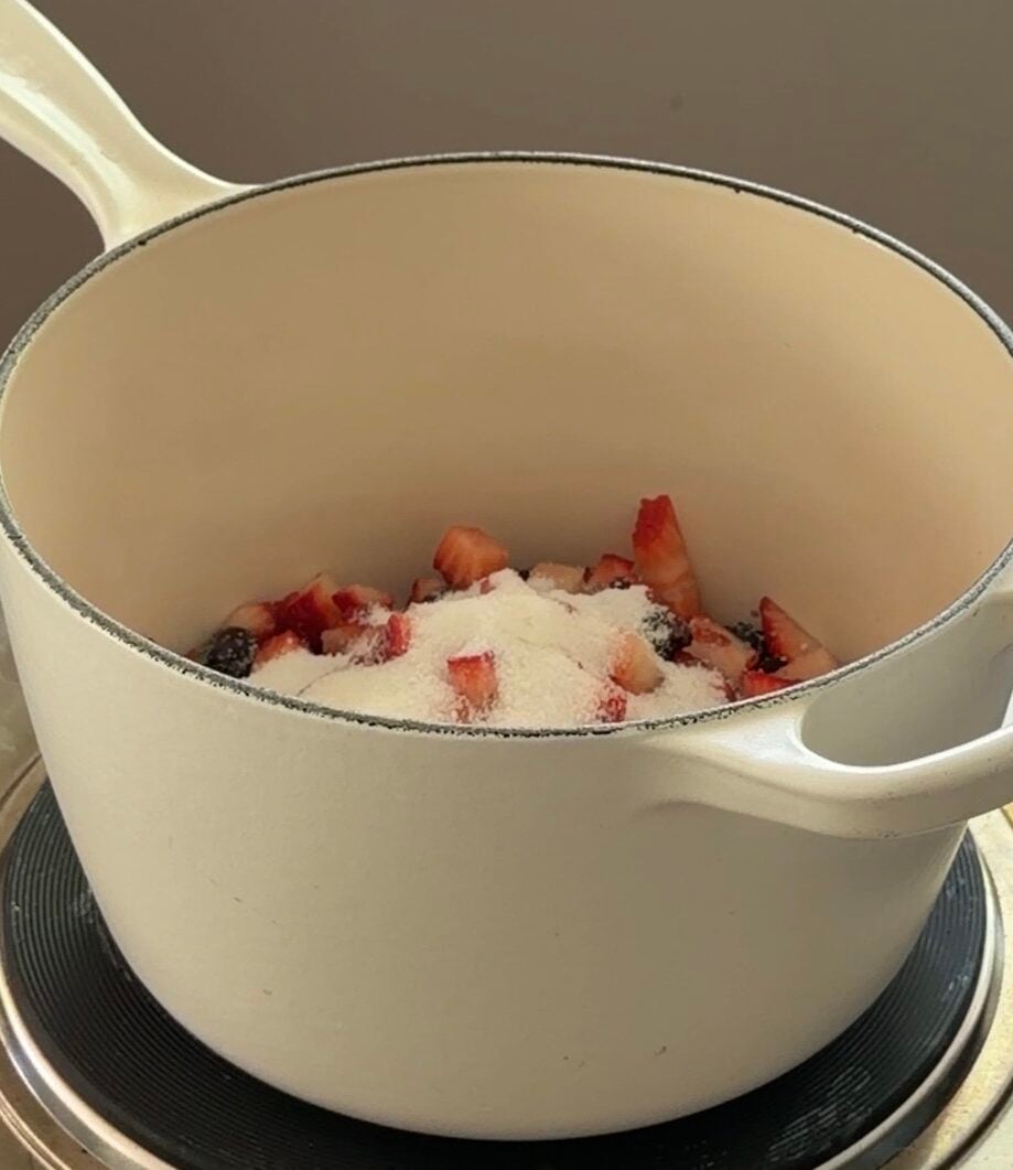Mixed berries and sugar cooking in a pot to make homemade berry sauce.