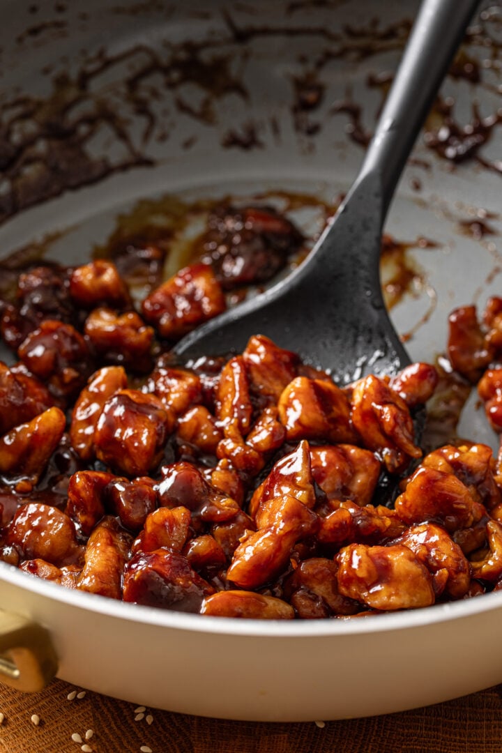 Close-up of homemade teriyaki chicken coated in a glossy sweet and savory sauce in a skillet.