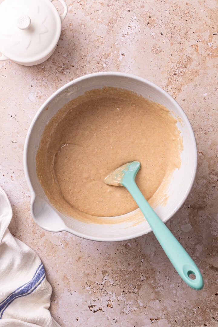 Churro cake batter mixed in a bowl with a spatula after adding the dry ingredients.