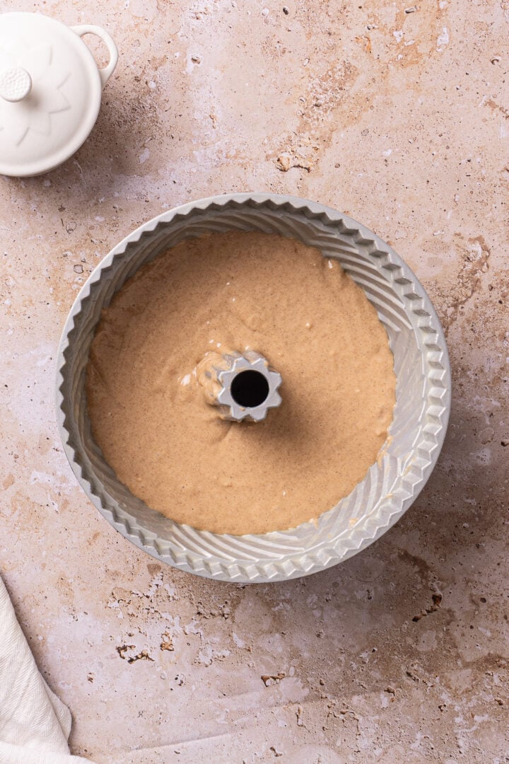 Cinnamon cake batter poured into a greased Bundt pan before baking.