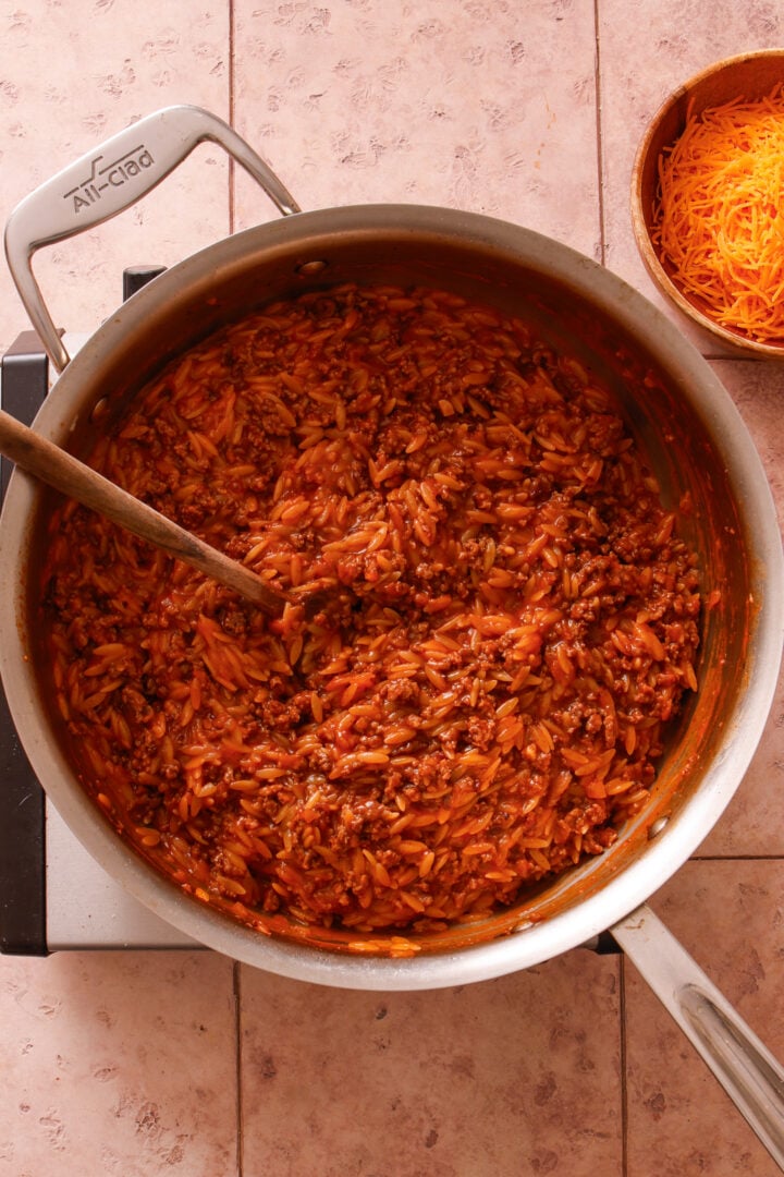 Ground beef and orzo simmering in tomato sauce before cheese is added.