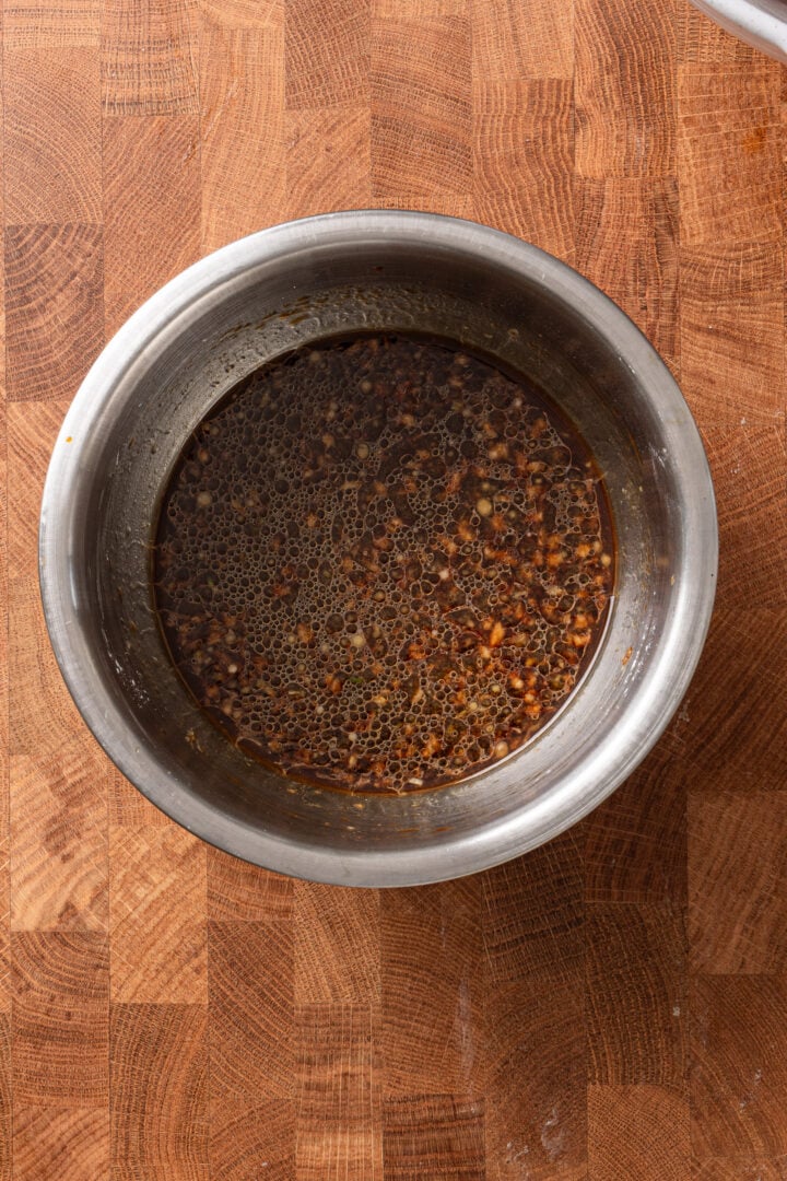 Homemade teriyaki sauce mixture with soy sauce, garlic, and ginger in a metal bowl.