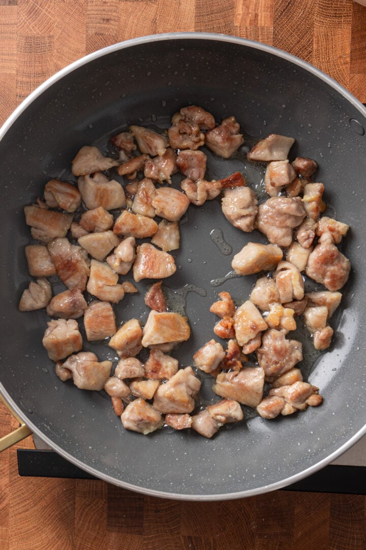 Bite-sized chicken pieces browning in a skillet while cooking for homemade teriyaki chicken.