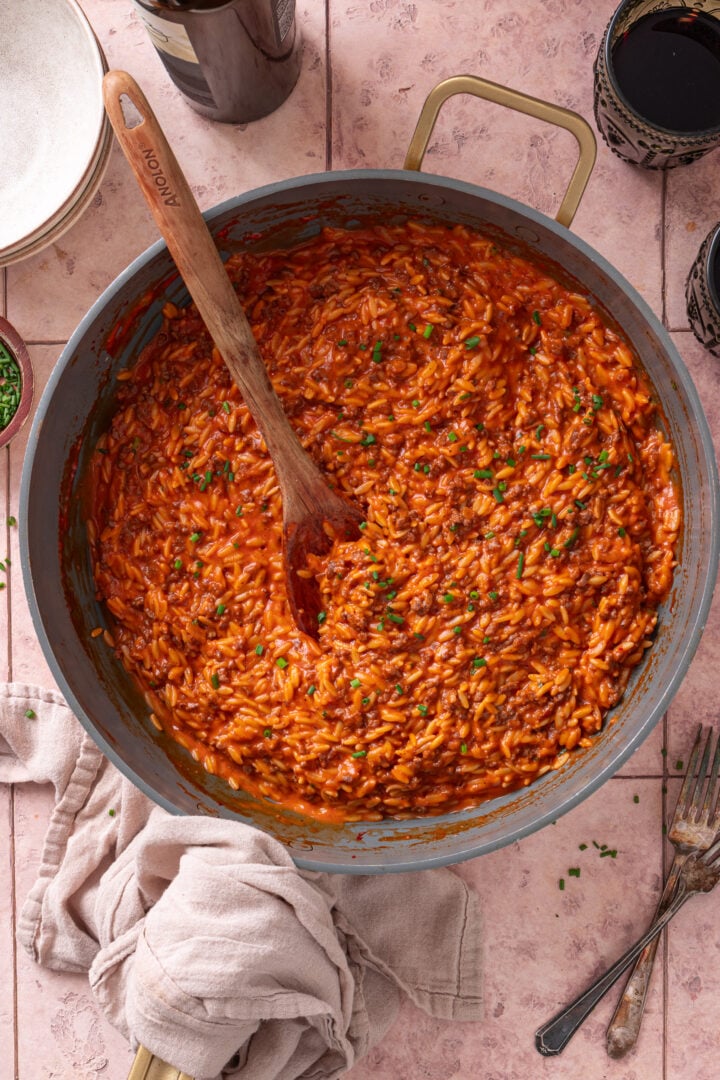 Skillet of creamy ground beef orzo topped with fresh chives.