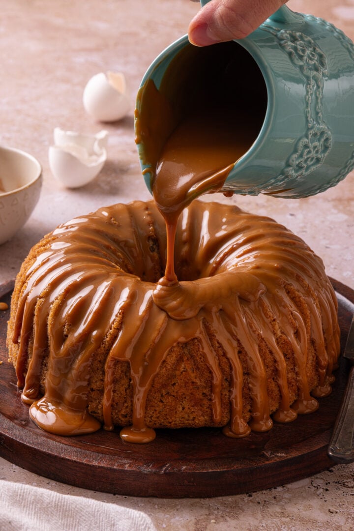 Pouring dulce de leche glaze over a homemade churro Bundt cake.