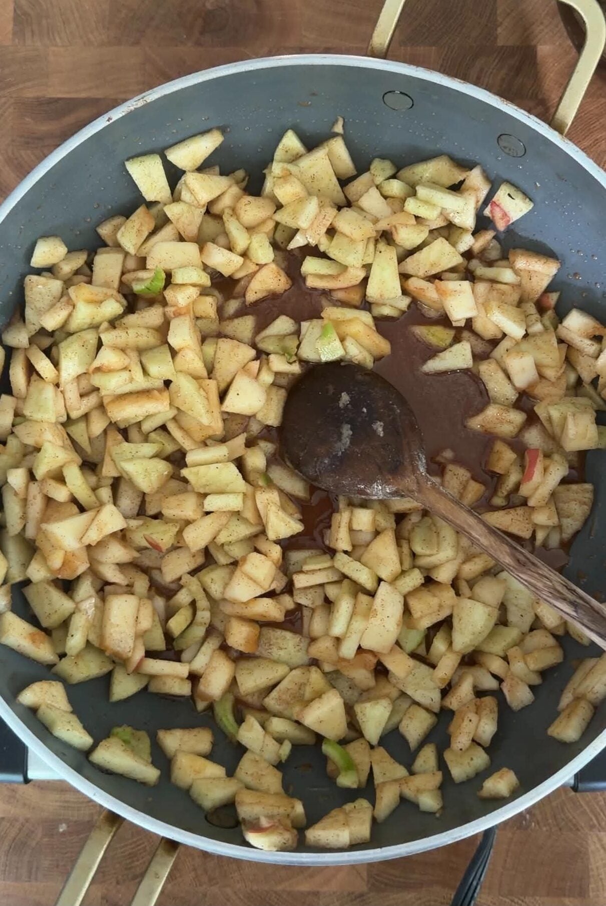 Diced apples cooking with honey, brown sugar, cinnamon and spices in a skillet for apple crumble bar filling.